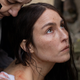 A woman looks blankly toward the sky as another woman cleans blood off her shoulder in a scene from You Won't Be Alone.